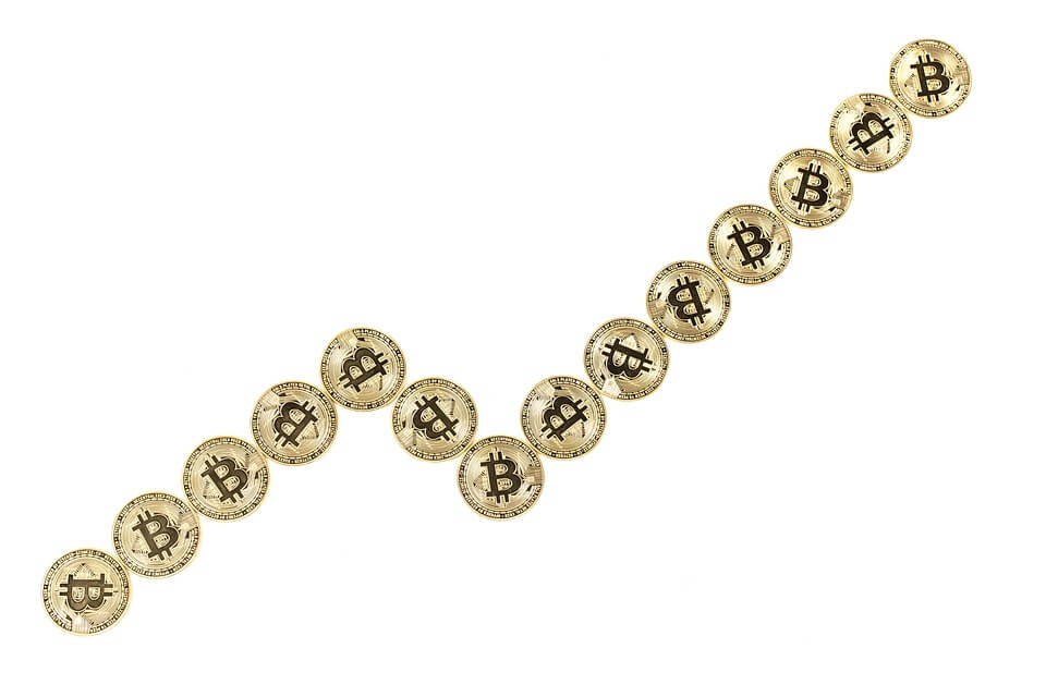 A series of gold-colored Bitcoin coins are arranged to form an upward trending arrow, symbolizing the potential of crypto trading.